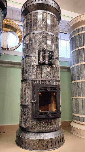 Full height Tundra Black amphibolite masonry heater standing in a showroom, showing polished stone finish for cabins