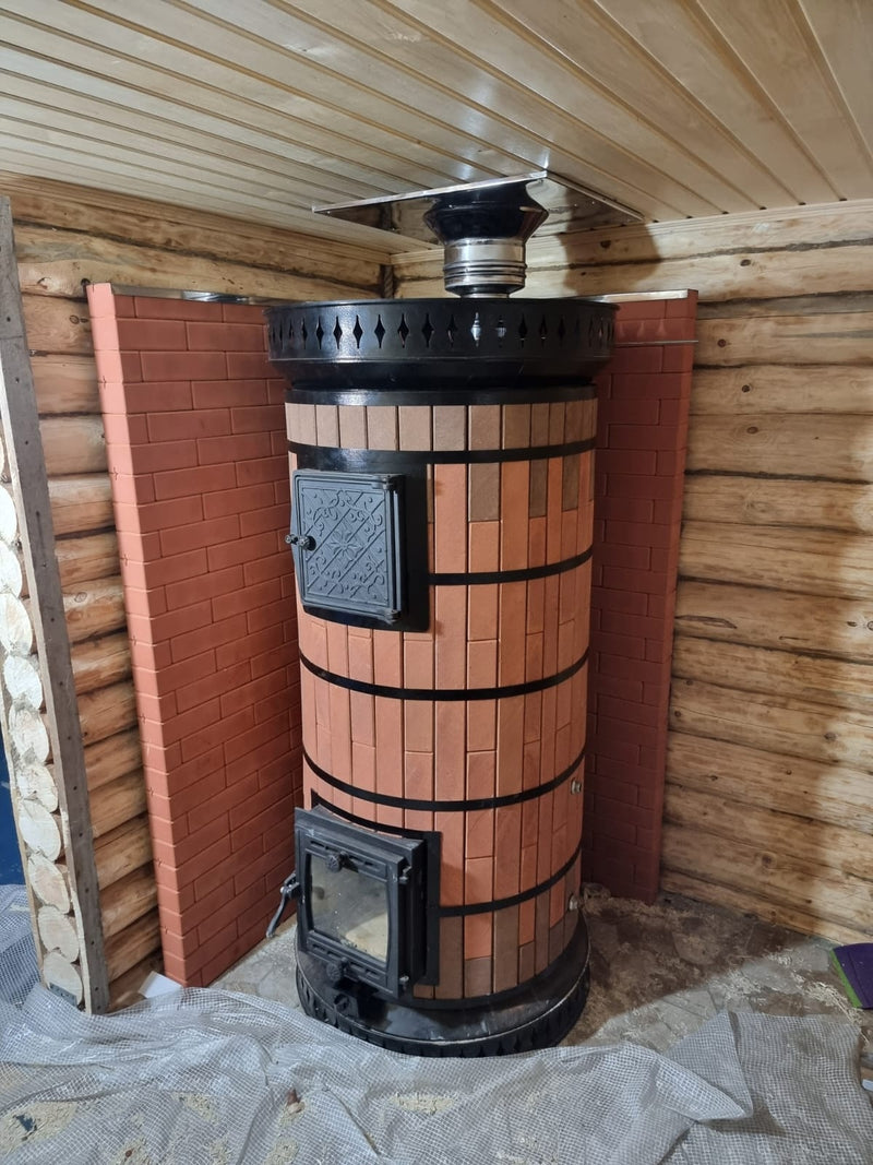 Custom red siberia brick masonry heater installed in log cabin sauna with stainless steel chimney