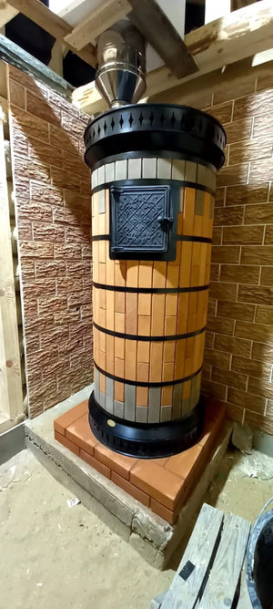 Decorative red masonry sauna heater with tan and grey brickwork, cast iron steel bands, and cast iron door