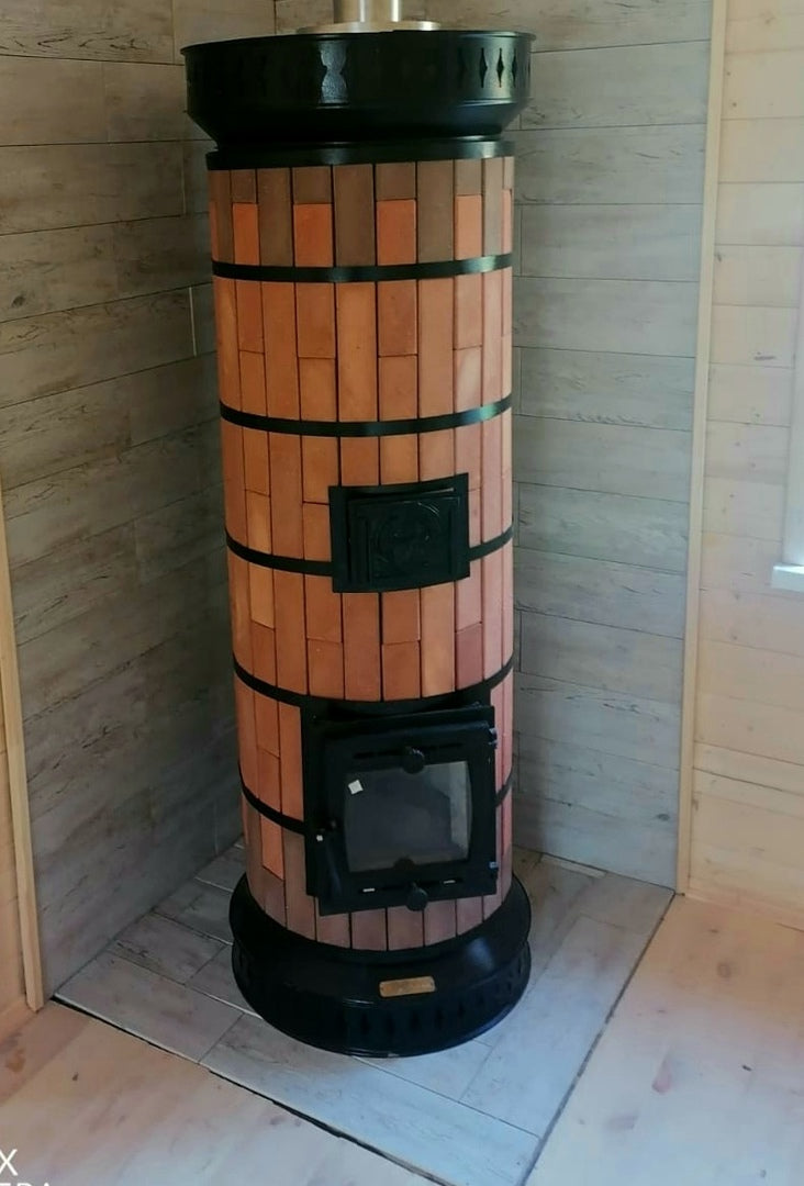 A red brick Tundra masonry heater installed in a wood-paneled corner, showcasing its space-saving cylindrical design.