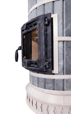 Side profile of cast iron door mounted on thick blue soapstone stone cladding of a DIY masonry heater kit