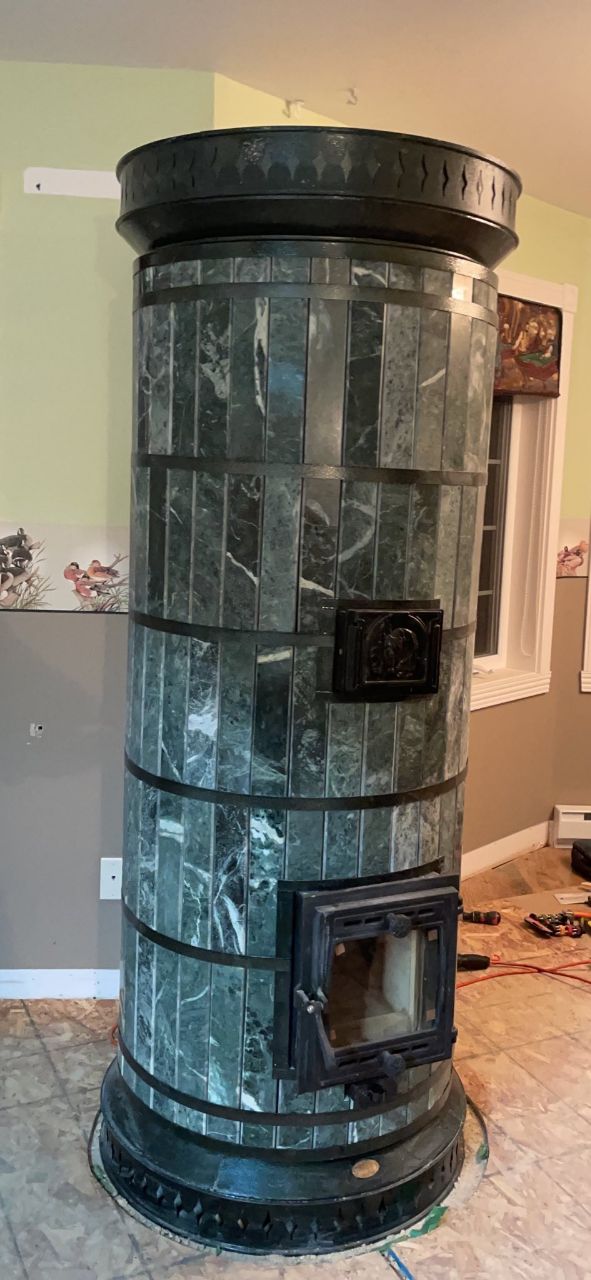 Close-up of a Siberia masonry heater with green serpentine stone tiles and carbon steel casing on a DIY masonry heater kit.