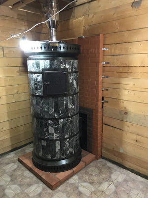 Installation of a black wood fired masonry sauna heater showing stainless steel chimney connection in a wooden sauna room