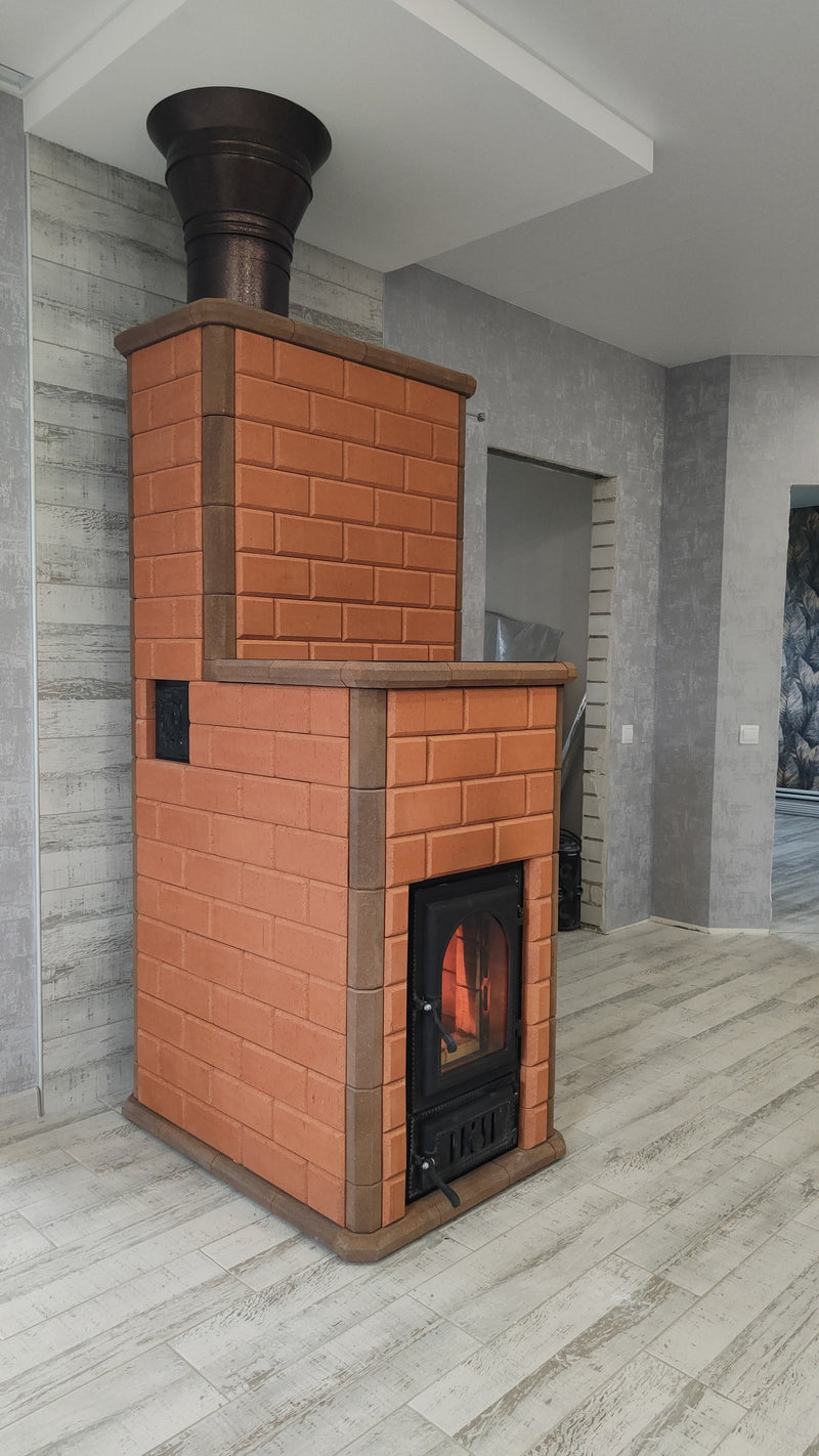 Side profile of the Lapland masonry heater, featuring a traditional red brick finish and a unique two-tiered stepped architectural design.