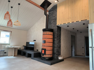 A Red Brick Siberia masonry heater installed in a modern living room with high vaulted ceilings and woven pendant lights.