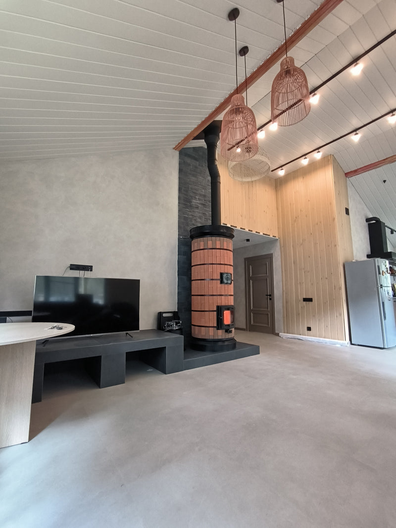 An open-concept home featuring a DIY red brick Siberia masonry heater as the central heating source between the dining area and kitchen.