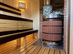 Side view of red brick sauna stove showing safe installation clearance from wooden benches and modern lighting