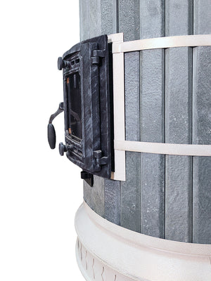 Side profile close-up of the Siberia blue soapstone masonry heater, showing the curved grey stone cladding, white banding, and heavy-duty cast iron door hinges.