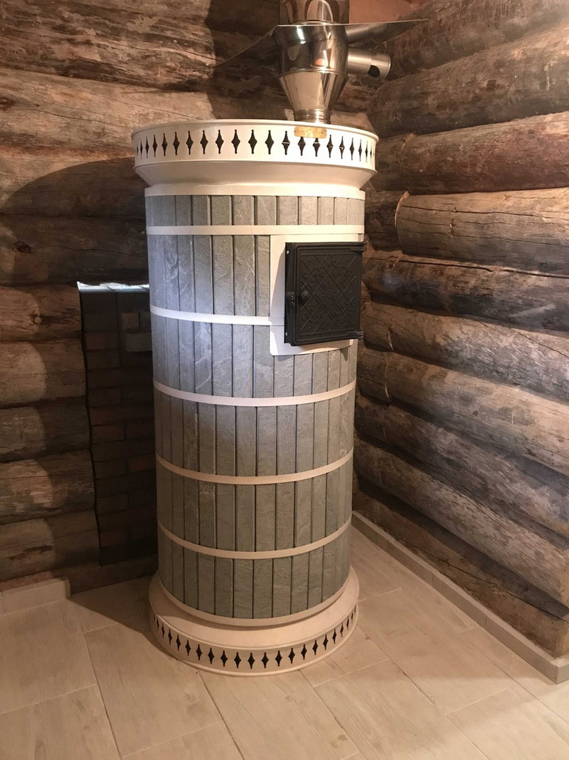 A premium Siberia model masonry sauna heater featuring grey soapstone cladding and white trim, installed in a rustic log cabin sauna with stainless steel venting.