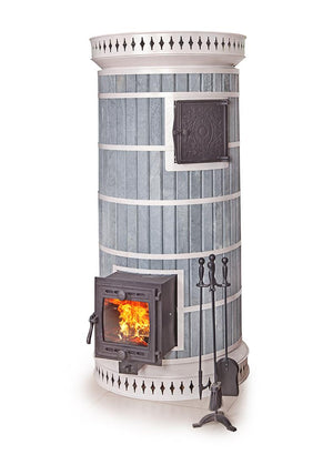 Round soapstone blue masonry heater with white metal banding and a glass door cast iron firebox with a fire burning inside. A set of fireplace tools stands next to the heater.