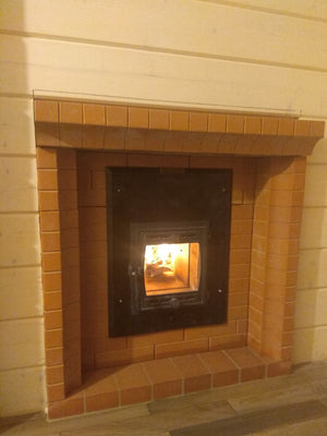 Cast iron firebox door of a masonry sauna heater installed in a portal brick