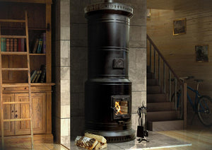 Venice-40 black steel masonry heater installed in a modern industrial loft with high ceilings, stone floors, and wooden library ladder