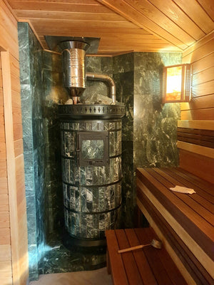 Green stone wood fired sauna stove loaded with sauna stones, installed in a cedar lined steam room